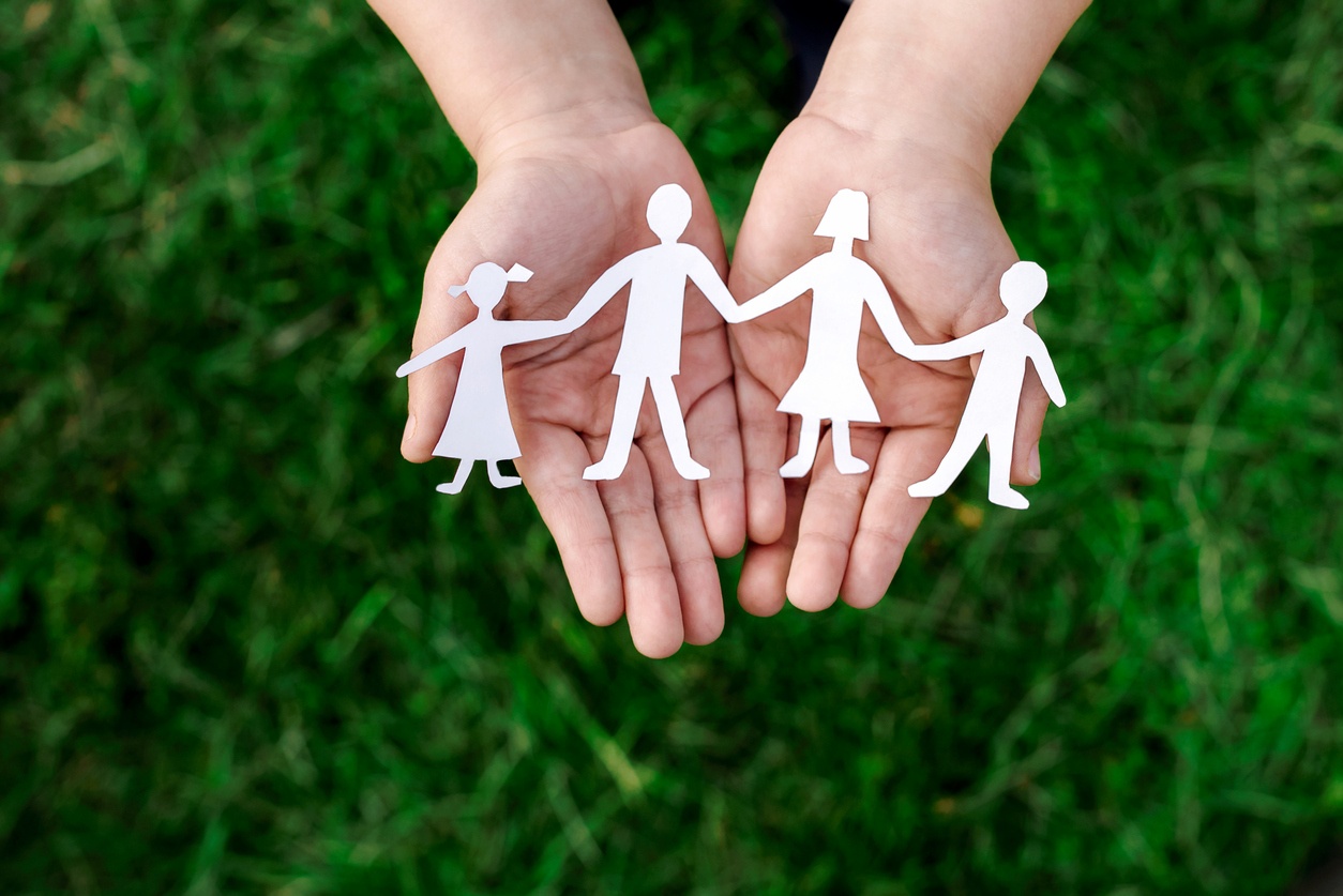 Hands holding a paper cut out of a family depicting wealth transfer